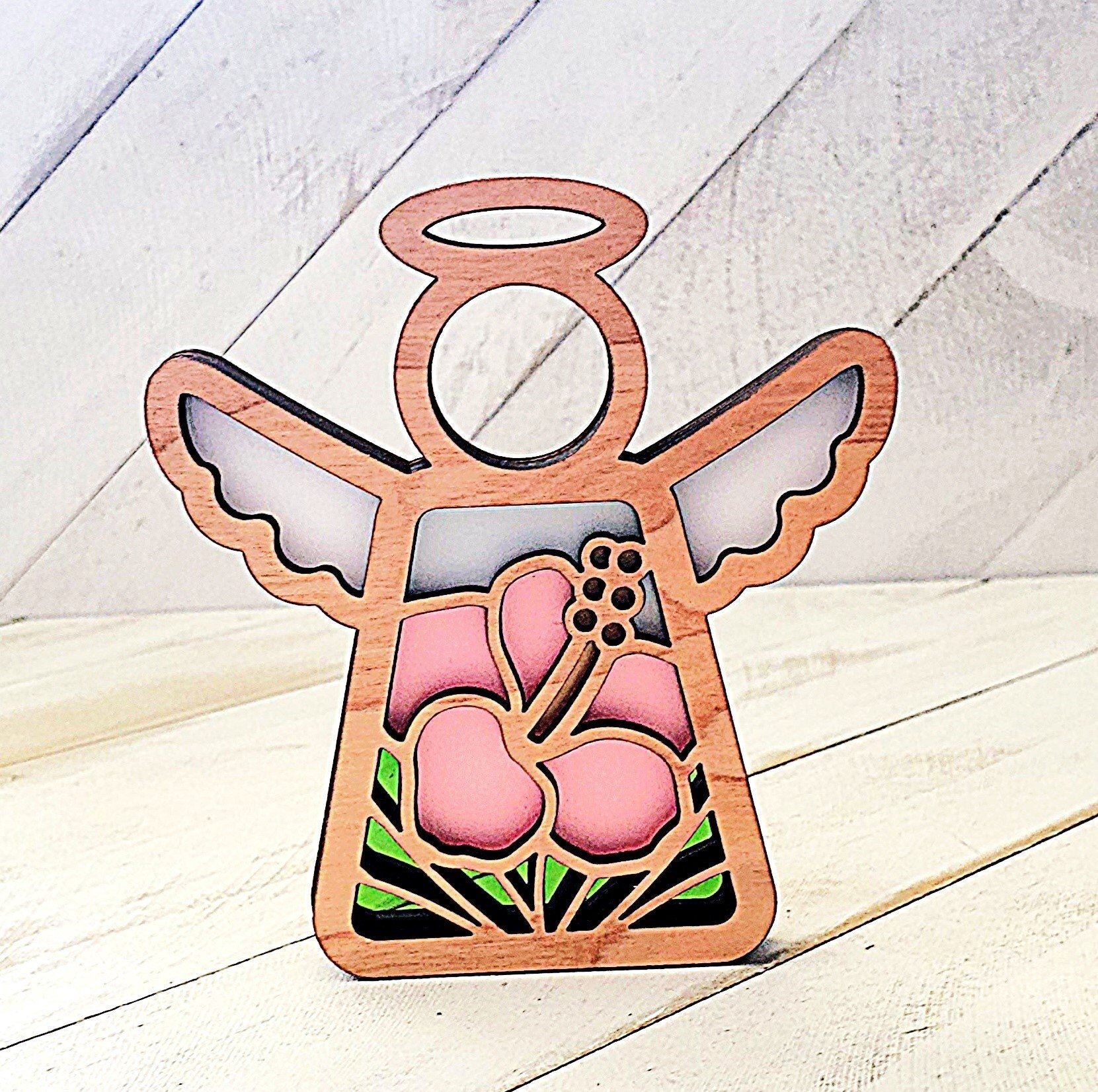 Handmade 3 layer laser cut wood and acrylic Pink Hibiscus Angel suncatcher ornament. The ornament is made with translucent acrylic which allows light to pass through the acrylic which gives the appearance of stained glass.