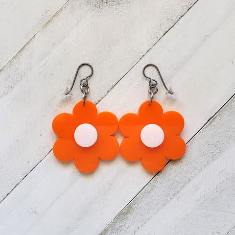 Retro Orange Flower with white center acrylic dangle earrings. 70&#39;s style flower power jewelry. measure 1 1/2&quot; in length, 1 1/2&quot; in width and 1/8&quot; in depth. The 20 gauge top shelf Niobium earring wires are 99.9% pure, nickel free and hypoallergenic.